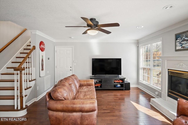 living area with stairs, ornamental molding, a textured ceiling, ceiling fan, and wood finished floors