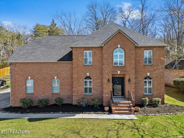 view of front of house with brick siding, roof with shingles, and a front yard