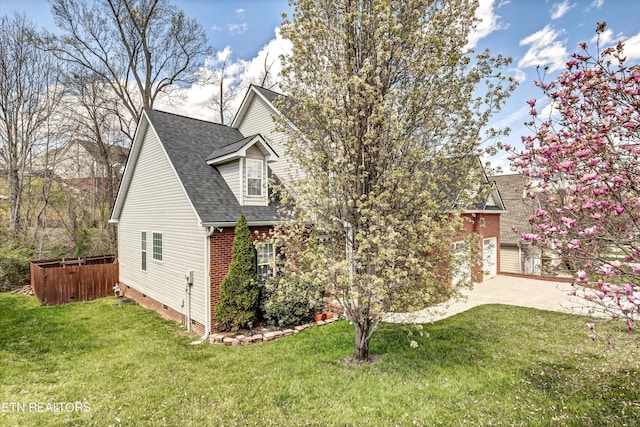 view of side of home featuring a lawn, a shingled roof, a patio area, and brick siding