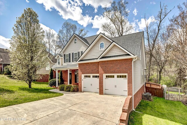 craftsman-style house with a front yard, concrete driveway, fence, brick siding, and a shingled roof