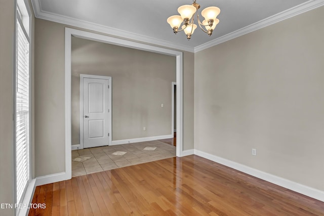 empty room featuring hardwood / wood-style floors, baseboards, a chandelier, and crown molding