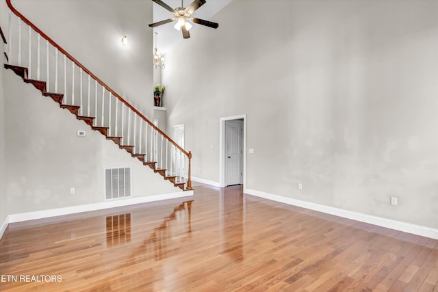 unfurnished living room featuring visible vents, stairway, a ceiling fan, and wood finished floors