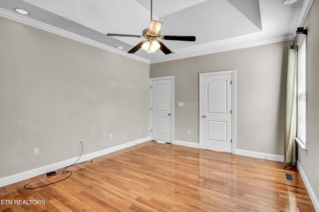 unfurnished bedroom featuring light wood-type flooring, ornamental molding, baseboards, visible vents, and a ceiling fan