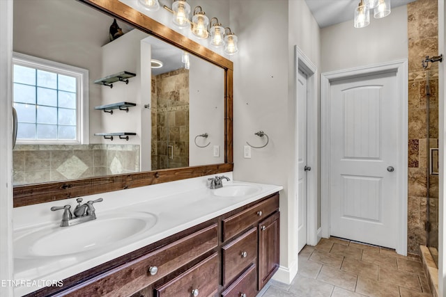 bathroom with double vanity, a sink, a tile shower, and tile patterned flooring