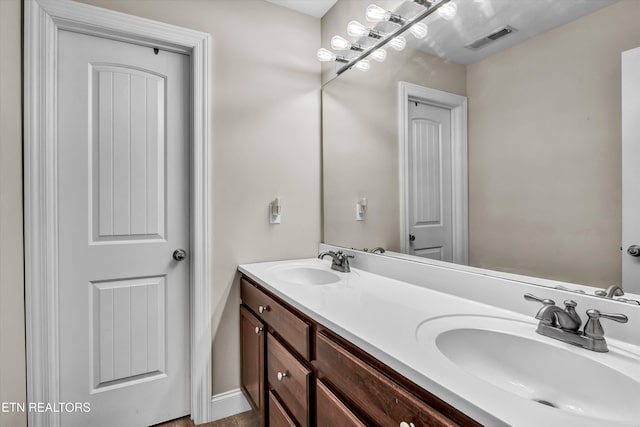 bathroom with visible vents, a sink, and double vanity