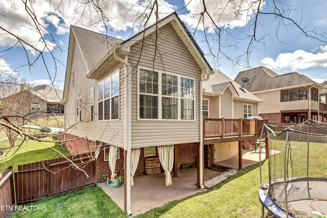 back of house featuring stairs, a trampoline, a fenced backyard, a patio, and a yard