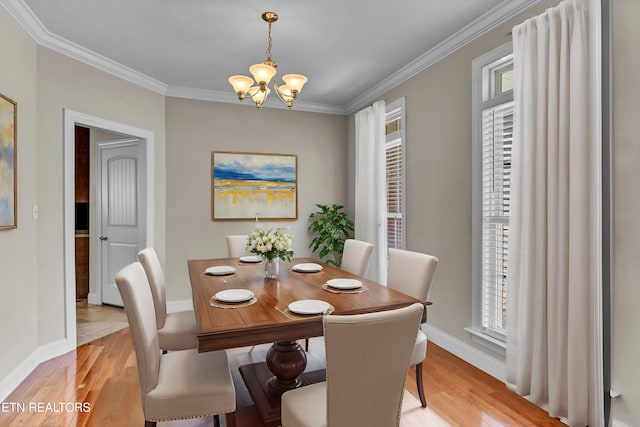 dining space with a wealth of natural light, a chandelier, light wood-type flooring, and ornamental molding