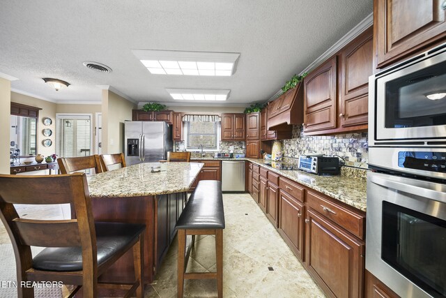 102 Baskins Creek Byp Unit 604, Gatlinburg, TN 37738 - kitchen with visible vents, crown molding, stainless steel appliances, tasteful backsplash, and a breakfast bar area