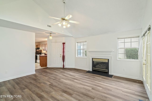 unfurnished living room with a fireplace with flush hearth, visible vents, ceiling fan, wood finished floors, and vaulted ceiling
