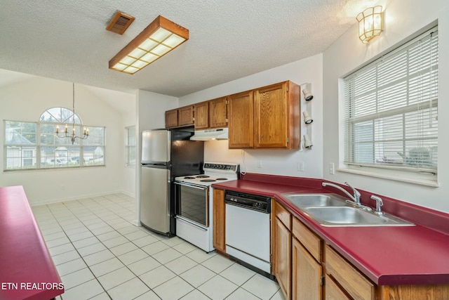 kitchen featuring white appliances, light tile patterned floors, under cabinet range hood, a sink, and a notable chandelier
