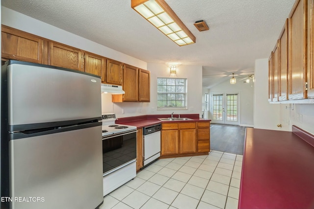 kitchen with white appliances, brown cabinets, a ceiling fan, under cabinet range hood, and a sink