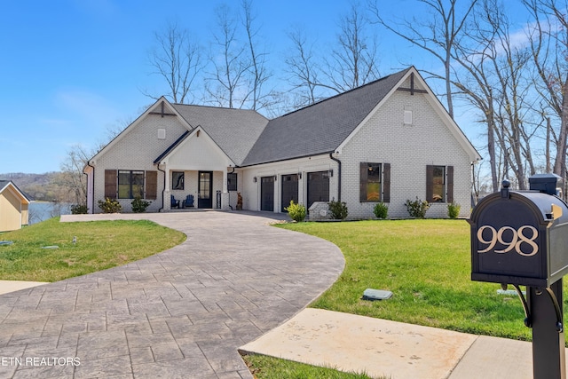 french country inspired facade with a front yard, an attached garage, curved driveway, and brick siding