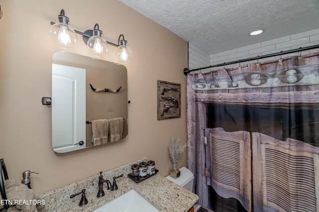 bathroom featuring toilet, vanity, curtained shower, and a textured ceiling
