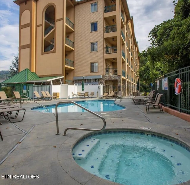 pool featuring a patio, a hot tub, and fence