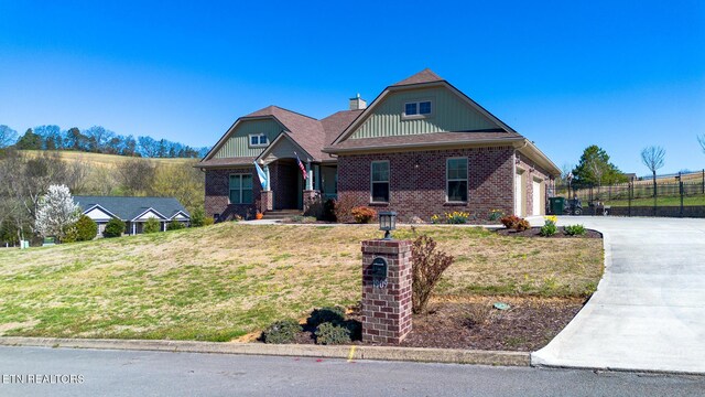 craftsman-style house with concrete driveway, a chimney, fence, brick siding, and a front lawn