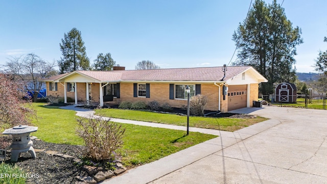 ranch-style home with an attached garage, a chimney, a front yard, brick siding, and driveway