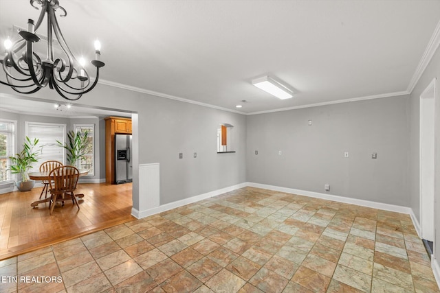 empty room featuring stone finish flooring, a notable chandelier, baseboards, and ornamental molding