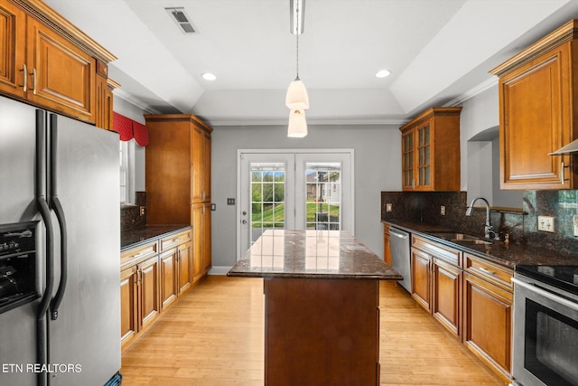 kitchen with stainless steel appliances, a tray ceiling, a sink, and a kitchen island