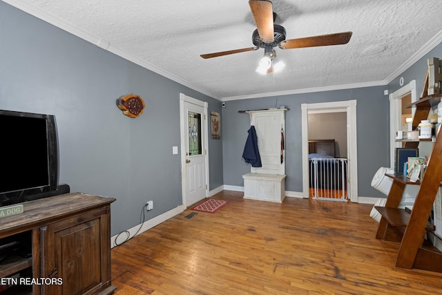 entrance foyer featuring a ceiling fan, wood finished floors, a textured ceiling, baseboards, and ornamental molding