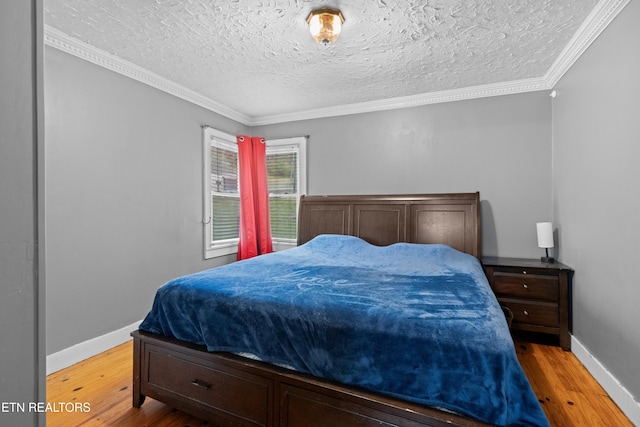 bedroom with baseboards, wood finished floors, ornamental molding, and a textured ceiling