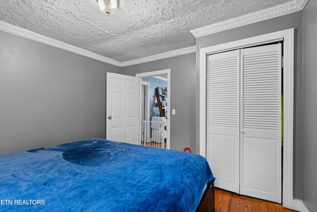 bedroom featuring ornamental molding, a textured ceiling, a closet, and wood finished floors