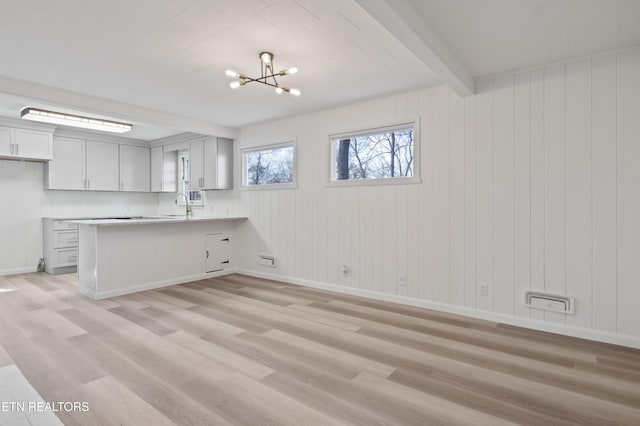 kitchen with beamed ceiling, light wood-style flooring, and a notable chandelier