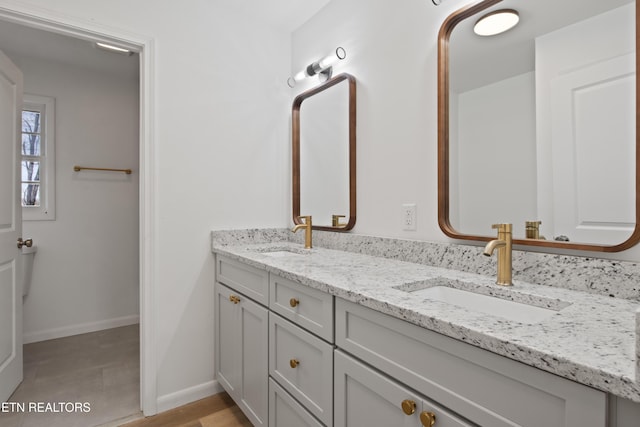 full bathroom with double vanity, baseboards, and a sink