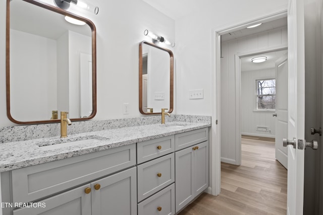 full bathroom with double vanity, wood finished floors, and a sink