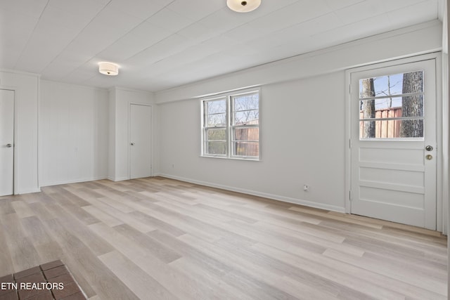 unfurnished room with light wood-type flooring, baseboards, and a wealth of natural light