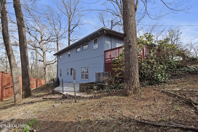 view of side of home with cooling unit, fence, and a deck