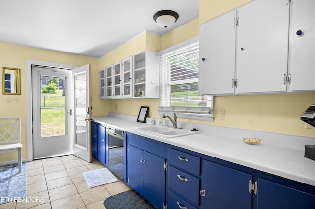 kitchen with light countertops, dishwasher, blue cabinets, a sink, and glass insert cabinets