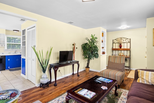 living area featuring baseboards, light wood finished floors, and visible vents