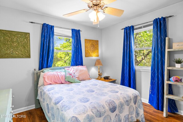 bedroom with a ceiling fan, wood finished floors, and multiple windows