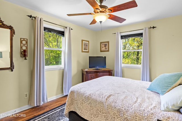 bedroom with baseboards, wood finished floors, ceiling fan, and multiple windows