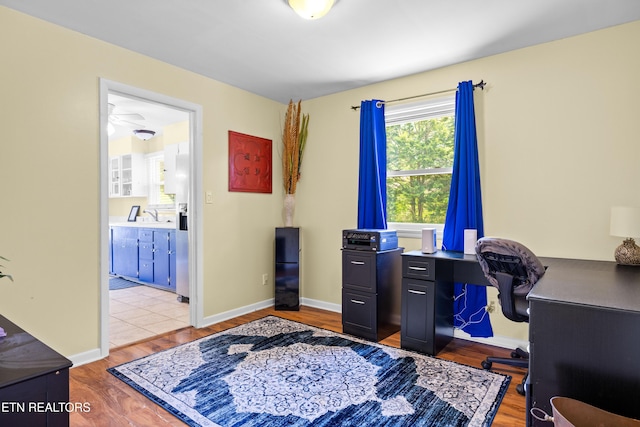 office area with baseboards, wood finished floors, and a sink