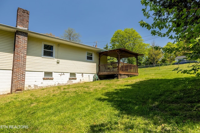 exterior space featuring a yard, a chimney, fence, and a deck
