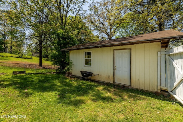 view of outdoor structure featuring fence and an outbuilding