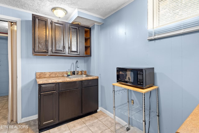 bar with crown molding, a sink, a textured ceiling, black microwave, and light tile patterned floors