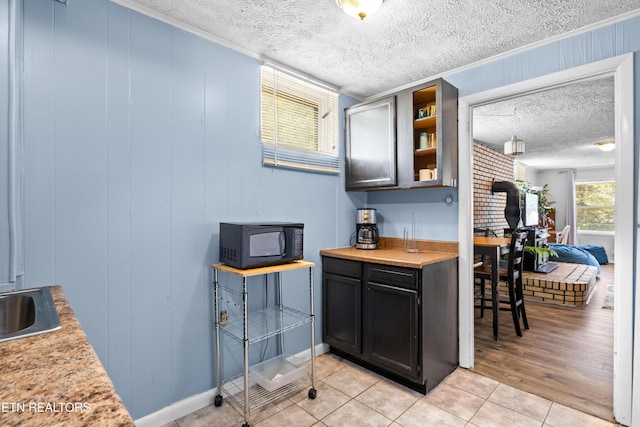 bar featuring light tile patterned floors, black microwave, a textured ceiling, and a wood stove