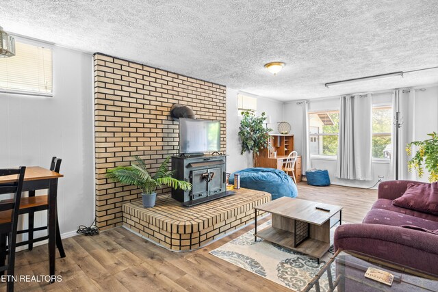 living room featuring a wood stove, wood finished floors, and a textured ceiling