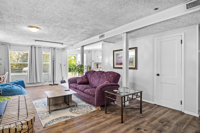 living room with wood finished floors, visible vents, and a textured ceiling