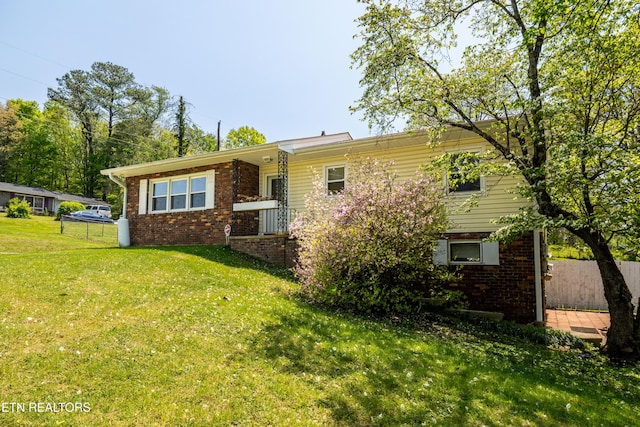 back of house with brick siding and a yard
