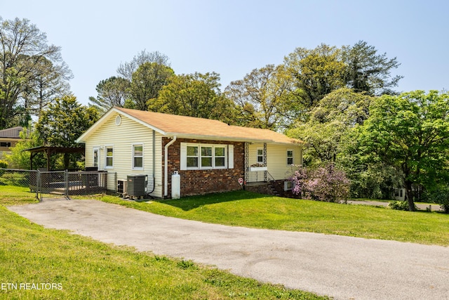 view of front of property featuring fence, brick siding, a front yard, and central AC unit