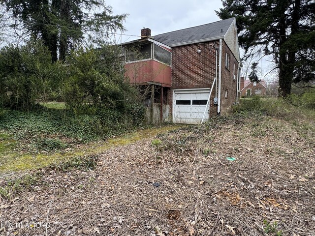 108 W Red Bud Rd, Knoxville, TN 37920 - view of side of property with an attached garage, a chimney, and brick siding