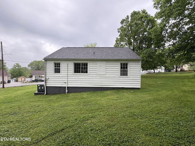 rear view of house with a yard and a shingled roof