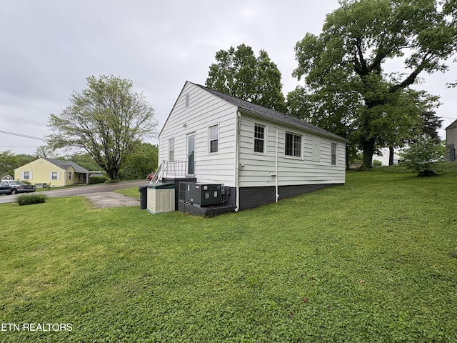 view of side of home featuring a lawn and central air condition unit