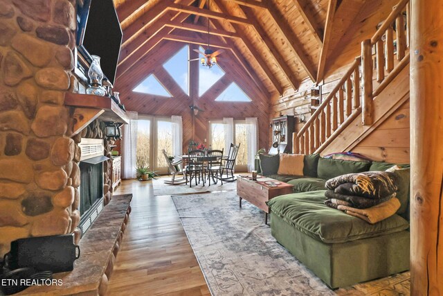 living area with ceiling fan, stairs, high vaulted ceiling, hardwood / wood-style flooring, and a fireplace