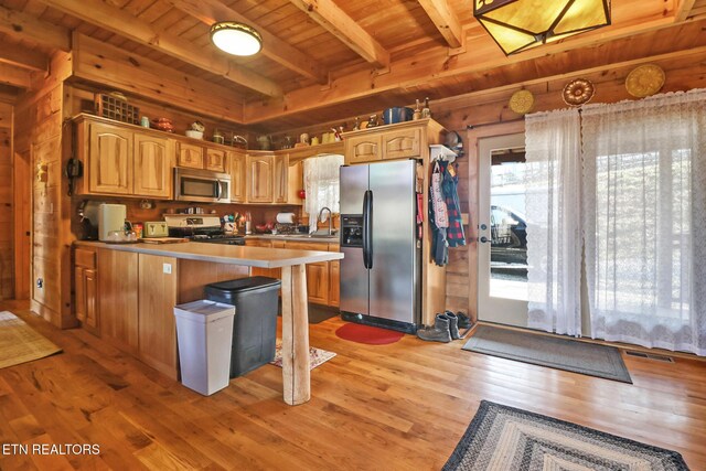 kitchen with a peninsula, appliances with stainless steel finishes, wooden ceiling, beamed ceiling, and light wood-style floors