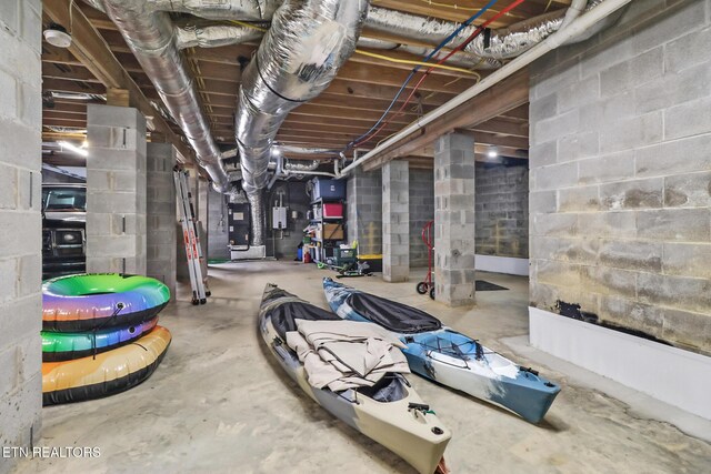 unfinished basement featuring heating unit and concrete block wall