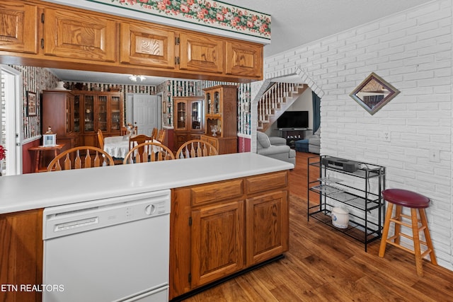kitchen featuring light countertops, brown cabinets, light wood finished floors, and dishwasher
